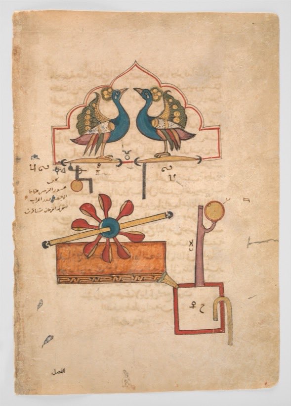 A page of aged paper covered in small Arabic script, with a coloured mechanical drawing laid over it. Two blue peacocks with fanned tails stand facing each other on a scalloped arch, each on a pivoted bar. Below them a red-bladed paddle wheel sits in an orange trough, with a spout leading down to a small square tank and a curved siphon tube.
